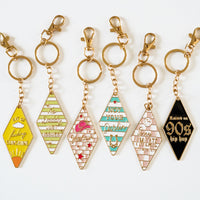 Retro motel keychain collection featuring vintage motel key tag style enamel keychains with gold hardware, colorful stripes, and playful sayings