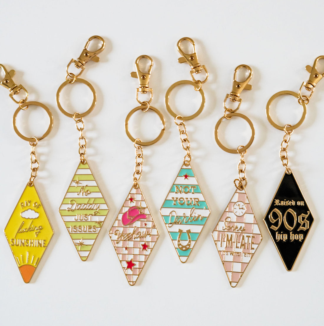 Retro motel keychain set featuring vintage-inspired enamel hotel key tag designs with gold metal ring and colorful slogans
