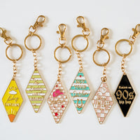 Retro motel keychain set featuring vintage-inspired enamel hotel key tag designs with gold metal ring and colorful slogans