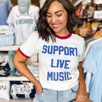 Woman wearing a t-shirt with 'Support Live Music' in a store setting