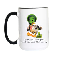 A white ceramic coffee mug with a black handle and black rim, featuring a cartoon illustration of a green-headed duck and a small green frog with the text 'girl you looks good wont you back that ass up' printed below.