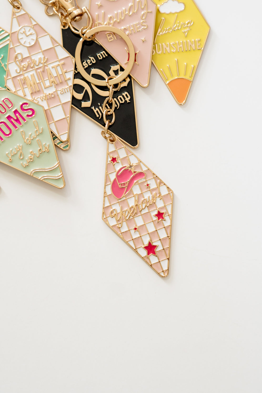 Close-up of retro motel keychains assortment with vintage key tag charms in pastel colors, gold hardware and engraved sayings