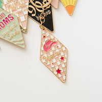 Close-up of retro motel keychains assortment with vintage key tag charms in pastel colors, gold hardware and engraved sayings