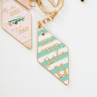 Vintage-style motel keychains reading "Not Your Darlin" and "My Other Ride is My Dad", pastel enamel tags with gold ring and retro design