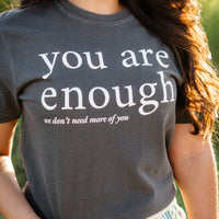 Person wearing a t-shirt with 'you are enough' text outdoors