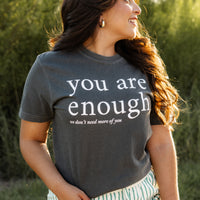 Woman wearing a t-shirt with 'you are enough' text in a natural setting