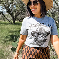 Person wearing a t-shirt with a cat graphic and 'MEOWDY' text outdoors.