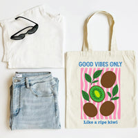 Tote bag with 'Good Vibes Only' design, white shirt, sunglasses, and jeans on a white background