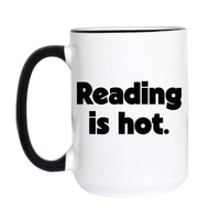 A white ceramic coffee mug with a black handle and black interior rim, featuring the text 'Reading is hot.' printed in bold black letters on the front.