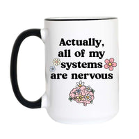A white ceramic mug with a black handle and black rim, featuring the printed text 'Actually, all of my systems are nervous' in black, decorated with small flowers and a pink brain illustration.