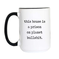 Funny quote coffee mug with black typewriter text reading "this house is a prison on planet bullshit." on a white mug with black accent handle and rim