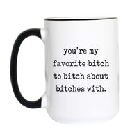 Funny best friend coffee mug with black typewriter text reading "you're my favorite bitch to bitch about bitches with" on a white mug with black accent handle and rim