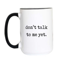 Not a morning person coffee mug with black typewriter text reading "don't talk to me yet." on a white mug with black accent handle and rim