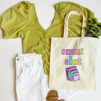 Green top, white pants, and tote bag with 'smut slut' text on a white background