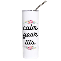 A white insulated tumbler with a clear lid and metal straw, printed with the phrase 'calm your tits' in black script and decorated with pink, peach, and green floral motifs above and below the text.