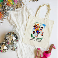 Tote bag with cartoon character and text, surrounded by disco balls and high heels on a white surface