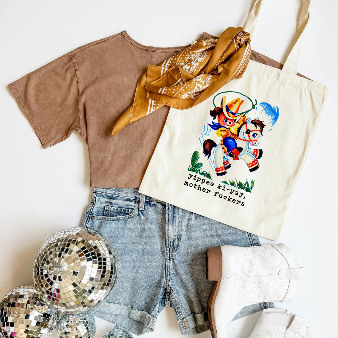 Brown t-shirt, denim shorts, gold scarf, and tote bag with graphic design on a white background