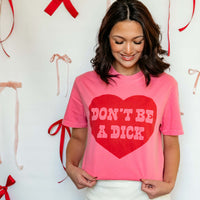 Woman wearing a pink t-shirt with a red heart and text, standing against a light background with decorative elements.