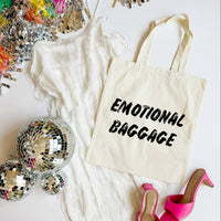 Tote bag with 'EMOTIONAL BAGGAGE' text, disco balls, and high heels on a white surface