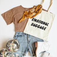 Brown t-shirt, denim shorts, gold scarf, 'EMOTIONAL BAGGAGE' tote bag, disco ball on a white background