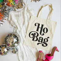 Tote bag with 'Ho Bag' text on a white surface with disco balls and high heels.