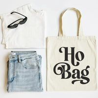 White tank top, blue jeans, black sunglasses, and a tote bag with 'Ho Bag' text on a white background