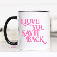 White mug with pink text 'I LOVE YOU SAY IT BACK' on a white background