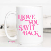 White mug with pink text 'I LOVE YOU SAY IT BACK' on a white background