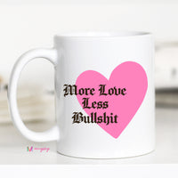 White mug with a pink heart and text 'More Love Less Bullshit' on a white background