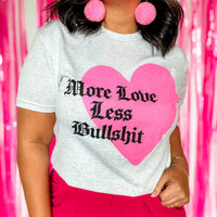 Person wearing a t-shirt with a pink heart and text against a pink curtain background