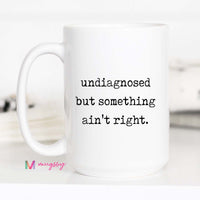 White mug with text 'undiagnosed but something ain't right' on a white background