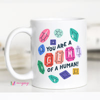 White mug with colorful gemstone designs and text on a white background