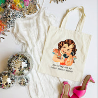 Tote bag with a graphic design and text, surrounded by disco balls and high heels on a white surface.