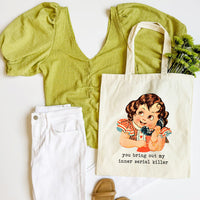 Green top, white pants, beige sandals, and tote bag with vintage illustration on a white background