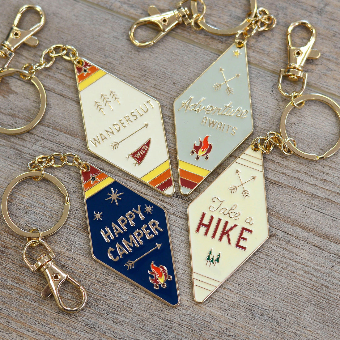 Camp Collection Soft Enamel Keychains - Happy Camper, Take a Hike, Adventure Awaits, and Wanderslut designs.