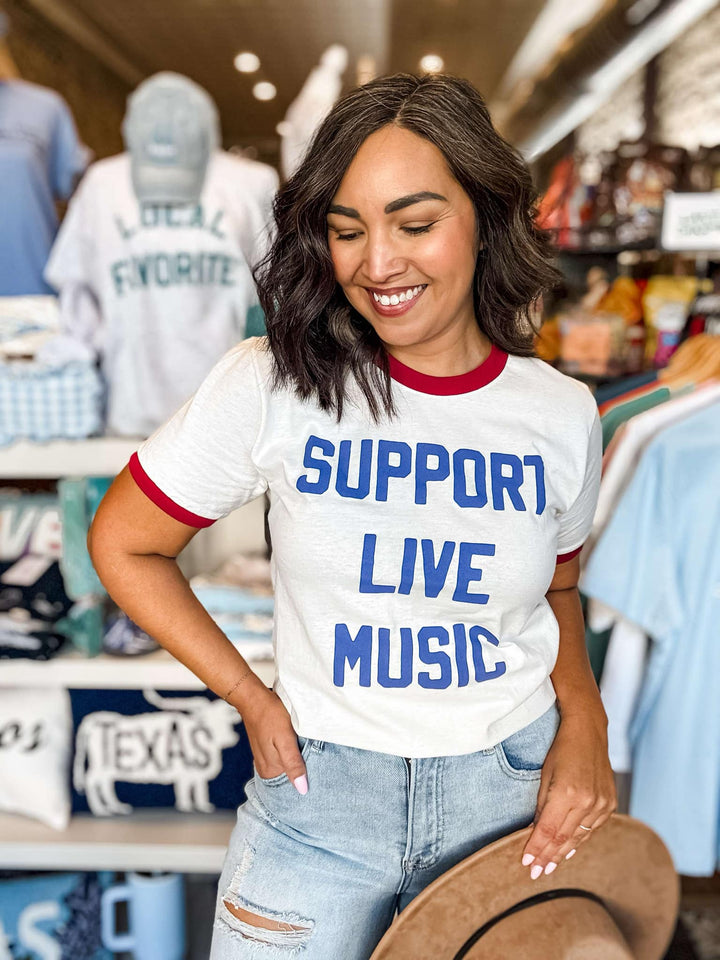 Woman wearing a t-shirt with 'Support Live Music' in a store setting