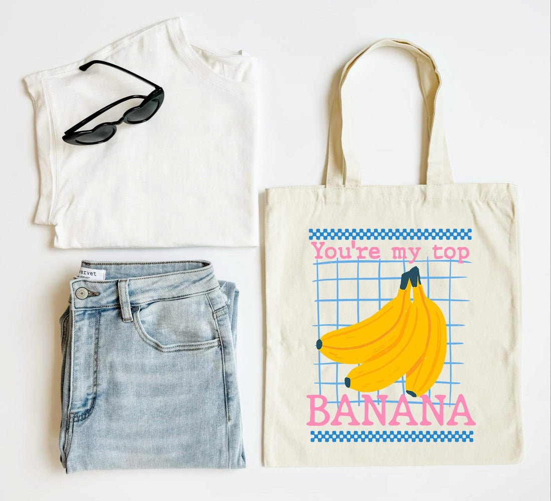 White t-shirt, blue jeans, black sunglasses, and a tote bag with banana design on a white background