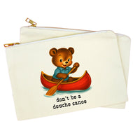 An off-white canvas zippered pouch featuring a cartoon illustration of a brown bear in a red canoe with the text 'don't be a douche canoes' printed below. A second pouch is partially visible behind it.