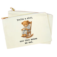 An off-white canvas zipper pouch featuring a teddy bear illustration sitting in a rocking chair, with the text 'You're a slut, and that makes me sad.' printed in black typewriter-style font.