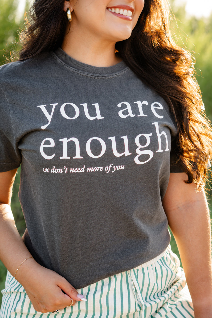 Person wearing a t-shirt with 'you are enough' text outdoors