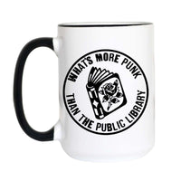 A white ceramic mug with a black handle and black rim, featuring a circular black graphic on the side that reads 'WHAT'S MORE PUNK THAN THE PUBLIC LIBRARY' around an illustration of an open book with a rose.