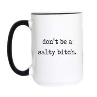 Funny sweary coffee mug with black typewriter text reading "don't be a salty bitch." on a white mug with black accent handle and rim