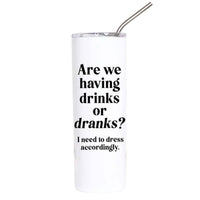 A tall, white insulated tumbler with a clear lid and metal straw, featuring the humorous text 'Are we having drinks or dranks? I need to dress accordingly.' in black font, set against a plain white background.