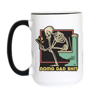 A white ceramic mug with a black handle and black rim, featuring a graphic of a skeleton sitting on a green toilet and holding a phone, with the text 'DOING DAD SHIT' in yellow.