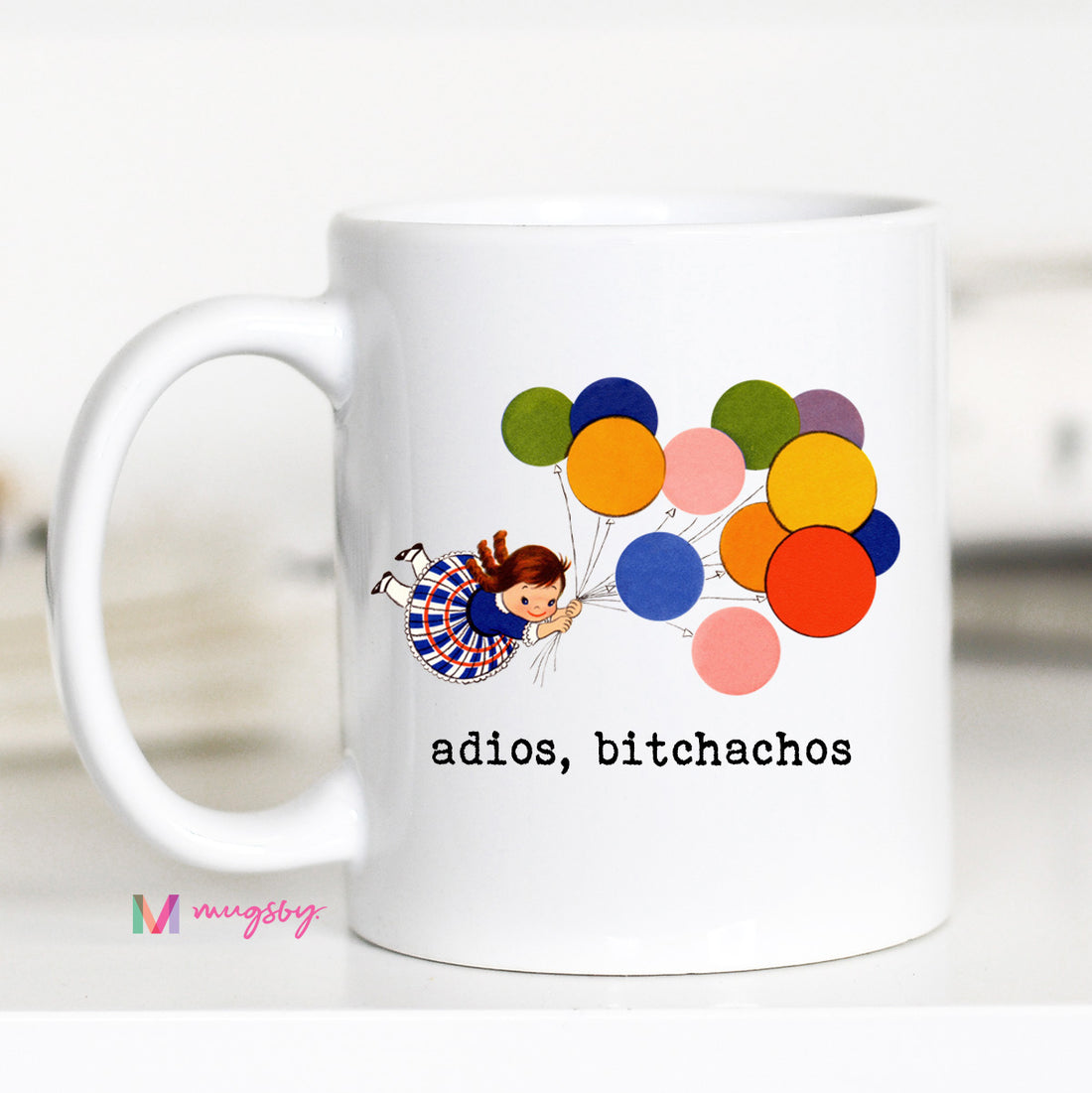 White mug with colorful balloons and a cartoon character, featuring the text &