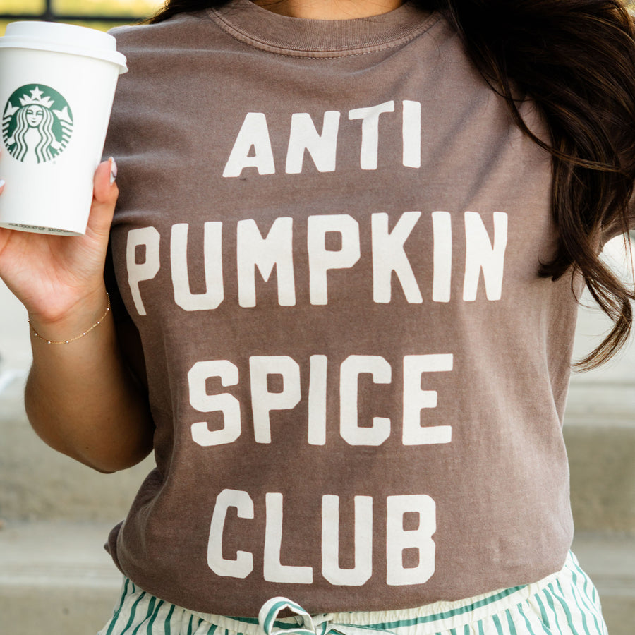 Person wearing a 'ANTI PUMPKIN SPICE CLUB' shirt holding a Starbucks cup.