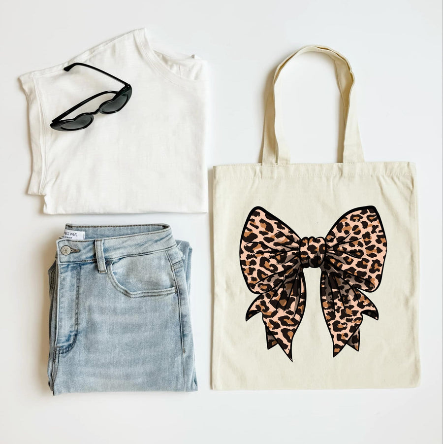 White sleeveless shirt, blue jeans, black sunglasses, and a tote bag with a leopard print bow on a white background.