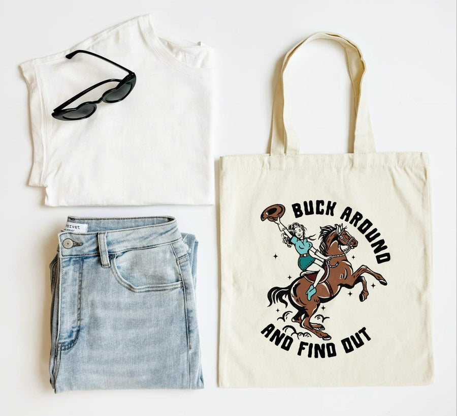 White tank top, blue jeans, sunglasses, and a tote bag with a horse and rider graphic on a white background.