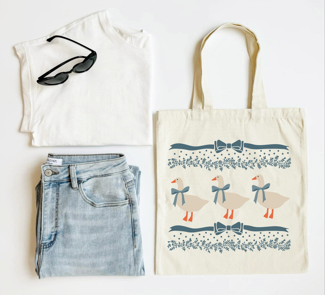 White tank top, blue jeans, sunglasses, and a tote bag with duck design on a white background