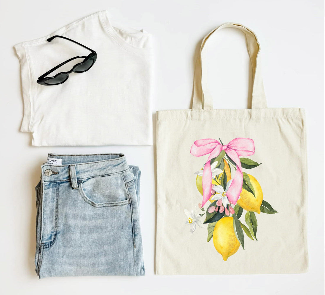 White tank top, blue jeans, sunglasses, and a tote bag with lemon design on a white background